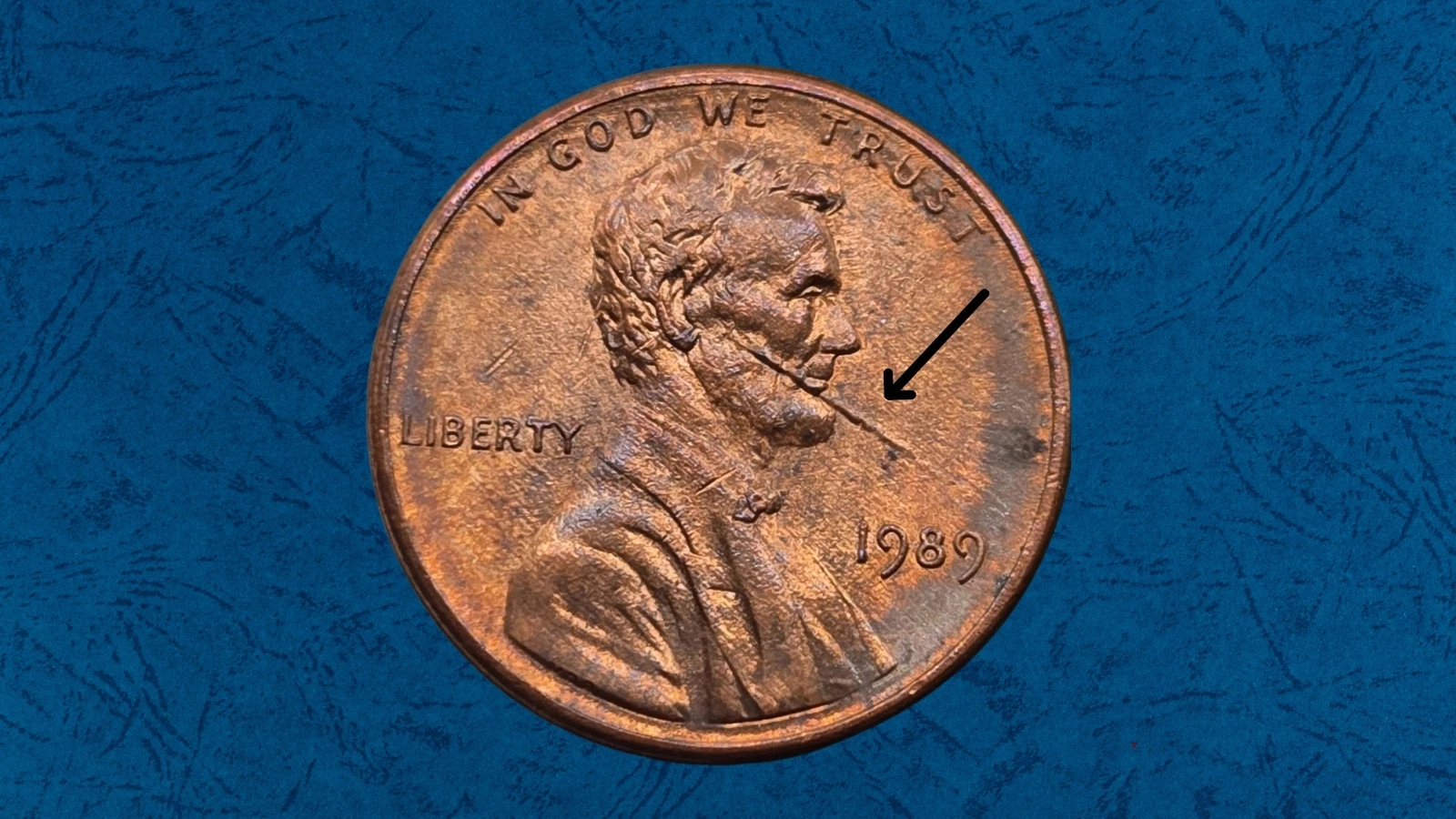 1989 Lincoln cent die cud error showing raised metal blob at rim covering part of IN GOD WE TRUST lettering